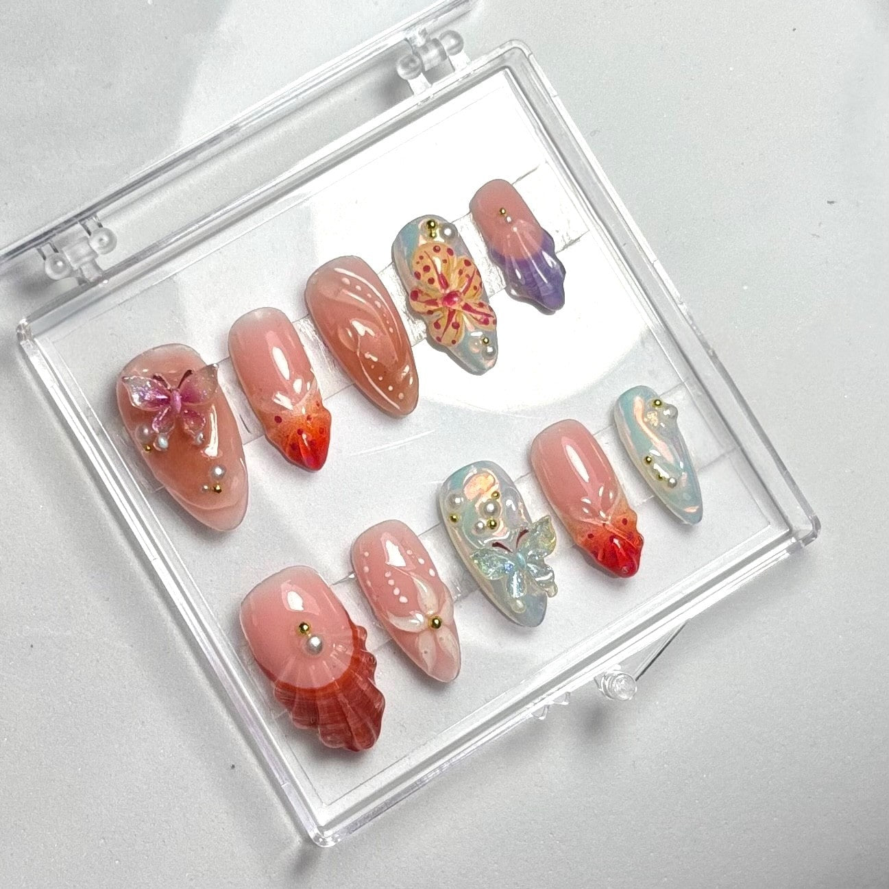 press on nails faits main réutilisables effet coquillage marron rouge et jaune et chromé et violet perle nacrée fleurs 3D papillon bijoux elfique 